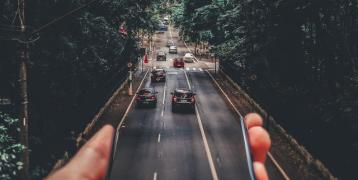 Person holding phone out of which a road appears Person holding phone out of which a road appears