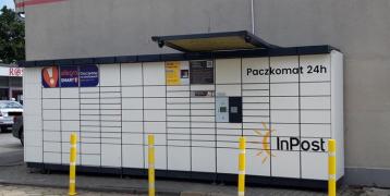 InPost, Automated Parcel Machine, Poznań, Poland The picture depicts an Automated Parcel Machine situated next to a local supermarket, close to a residential neighborhood.