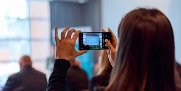 Woman taking photo during presentation Woman taking photo during presentation